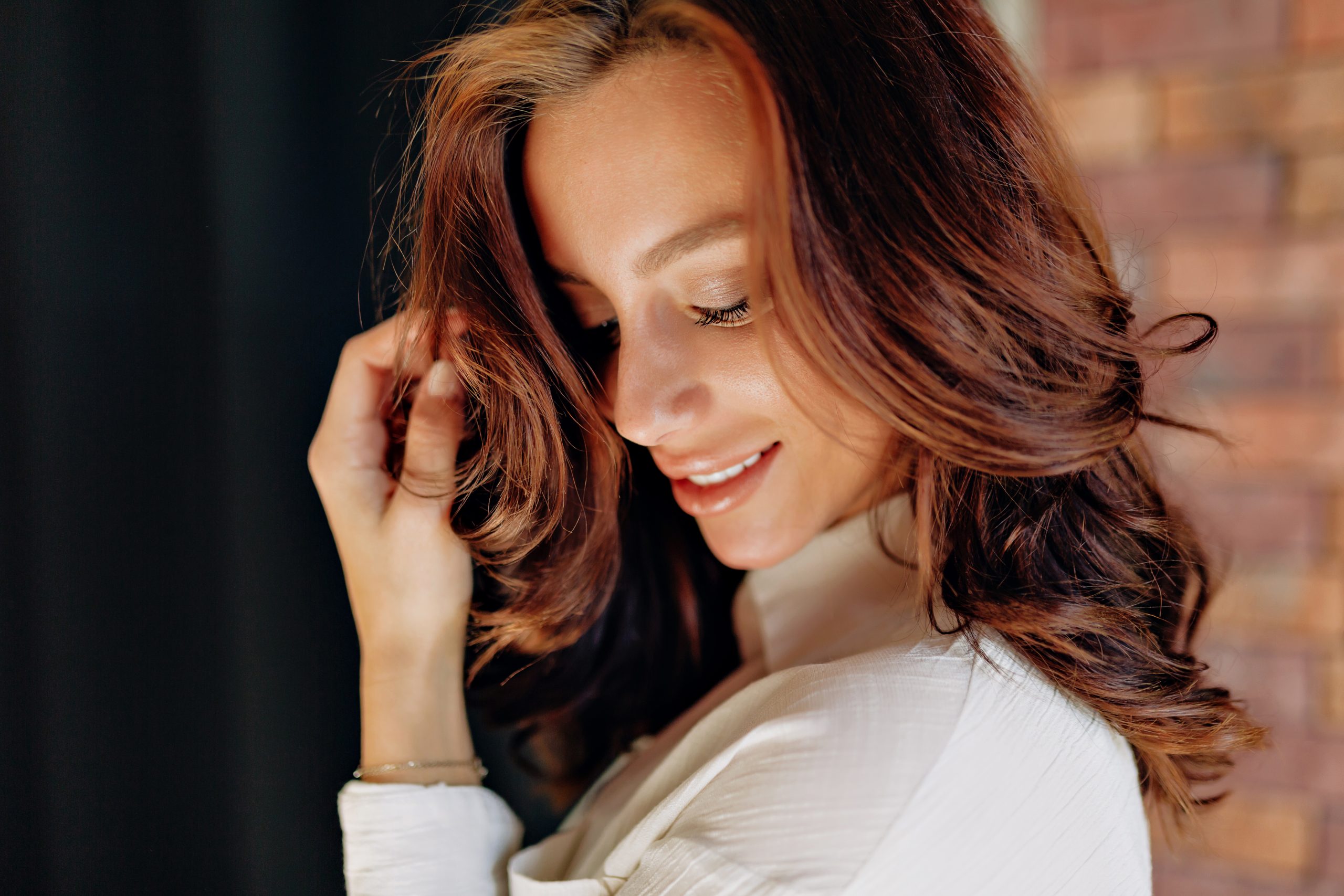 close-up-portrait-attractive-european-woman-with-curly-hair-posing-black-wall-smiling